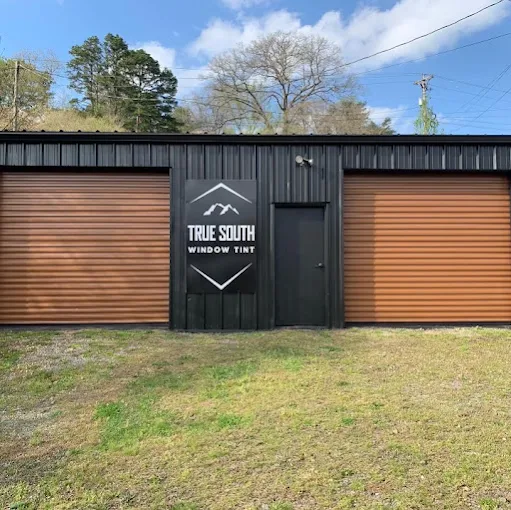 Exterior of the True South Window Tint shop, a black metal building with brown roll-up doors
